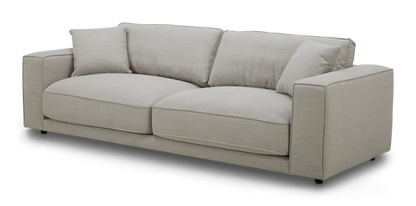 The Elmore Sofa, featuring a contemporary light gray design with plush cushions and wide armrests, is set against a black background.