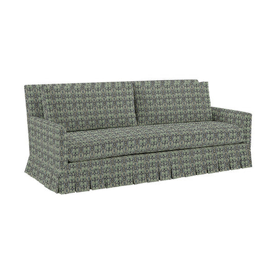 The Suzanne Kasler Mathes Sofa with Box Pleat Skirt is a three-seater featuring geometric green and black patterned fabric. It includes straight armrests, two seat cushions, and a fitted skirt that conceals the legs, while the fabric design enhances the decorative appeal of the upholstery.