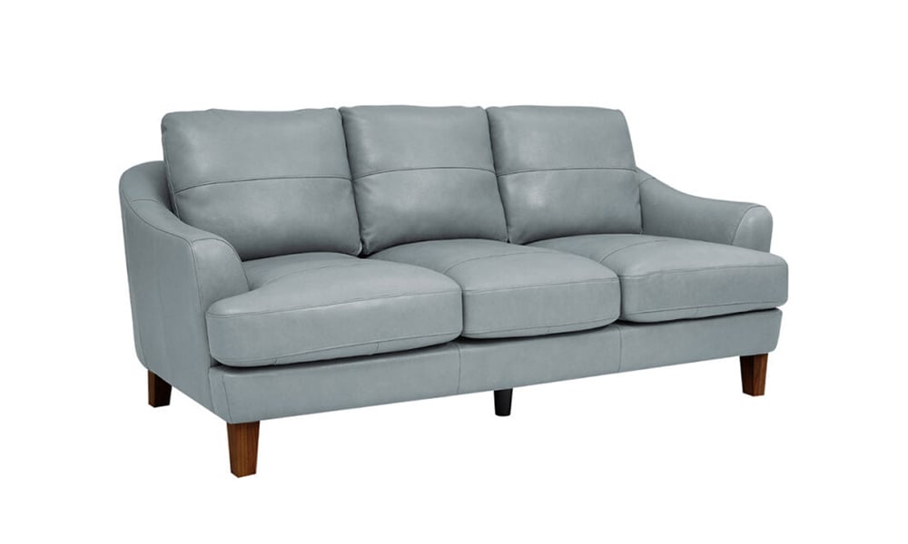 The Palmer Ice Leather Sofa features a light gray leather finish with three seat cushions and three back cushions. It boasts wooden legs and a modern, slightly curved design.