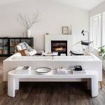 Apartment 34 lifestyle and home decor and interior design blog. White airy modern living room with white fluted curved edge sofa table, white upholstered couch with down cushions and flared walnut wood legs, white plaster fireplace, white clay vase, rattan wood accent chair.
