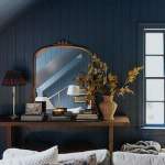 Chris Loves Julia lifestyle and home decor and interior design blog. Modern moody bedroom with dark blue Farrow and Ball painted paneled walls, gold framed mirror, natural wood display table.