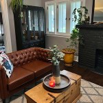 DIY Playbook lifestyle and home decor and interior design blog. Living room with vintage saddle brown leather Chesterfield style sofa, rustic farmhouse style wooden chest coffee table, terracotta pot, black painted display cabinet, and black fireplace.