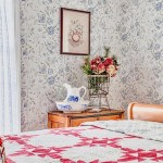 Dabbling and Decorating lifestyle and home decor and interior design blog. Rustic farmhouse vintage style bedroom with antique quilt, floral French blue wallpaper, antique ceramic decor, wire frame basket vase, and wood frame vintage cross-stitch.