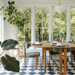 Style by Emily Henderson lifestyle and home decor blog. Conservatory sun room dining room. Argyle blue tile floor, rustic farmhouse dining table, sage green upholstered dining chairs.