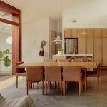The Design Files lifestyle and interior design blog. Danish modern kitchen and dining room with natural teak wood cabinets, leather and wood dining chairs, and polished concrete floor.