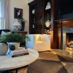 The Nesting Place lifestyle and home decor blog. Photo shows a white, channel-tufted chair with a circular marble coffee table, dark oak display cases, and a dark oak fireplace with green marble tile